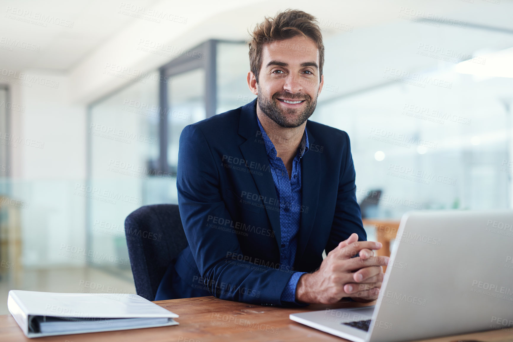 Buy stock photo Shot of a young businessman sitting at a desk in front of a laptop