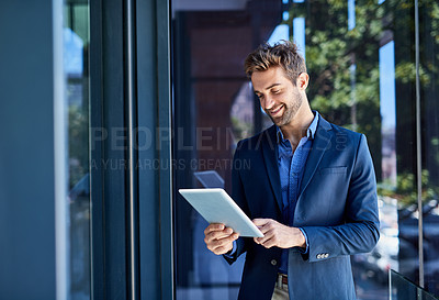 Buy stock photo Shot of a young businessman busy on a digital tablet