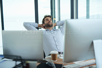Buy stock photo Shot of a young corporate businessman taking a break at an office desk
