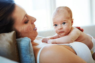 Buy stock photo Shot of a mother lying down with her newborn baby on top of her