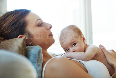 Buy stock photo Shot of a mother lying down with her newborn baby on top of her