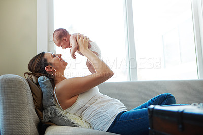 Buy stock photo Shot of a mother holding her newborn baby while lying down on a couch