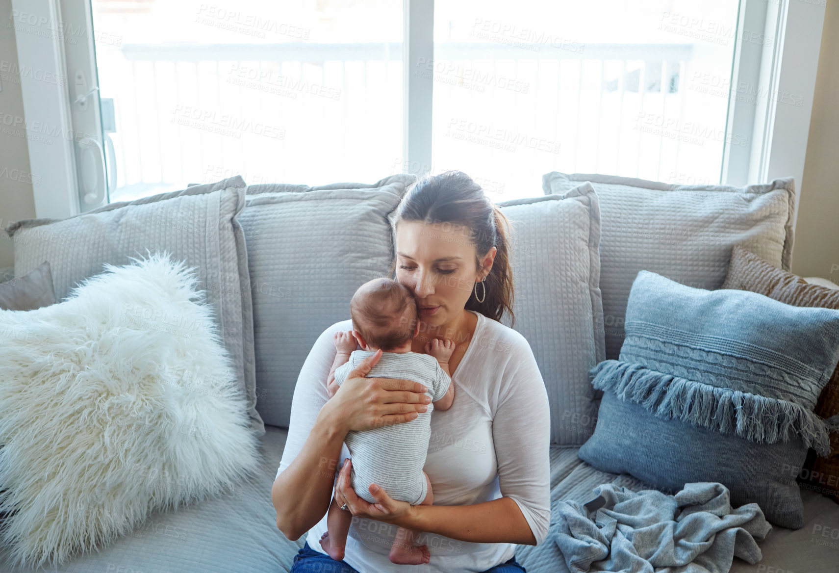 Buy stock photo Shot of a mother sitting with her newborn baby on a couch