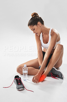 Buy stock photo Cropped shot of a young woman holding her injured foot that's highlighted in red