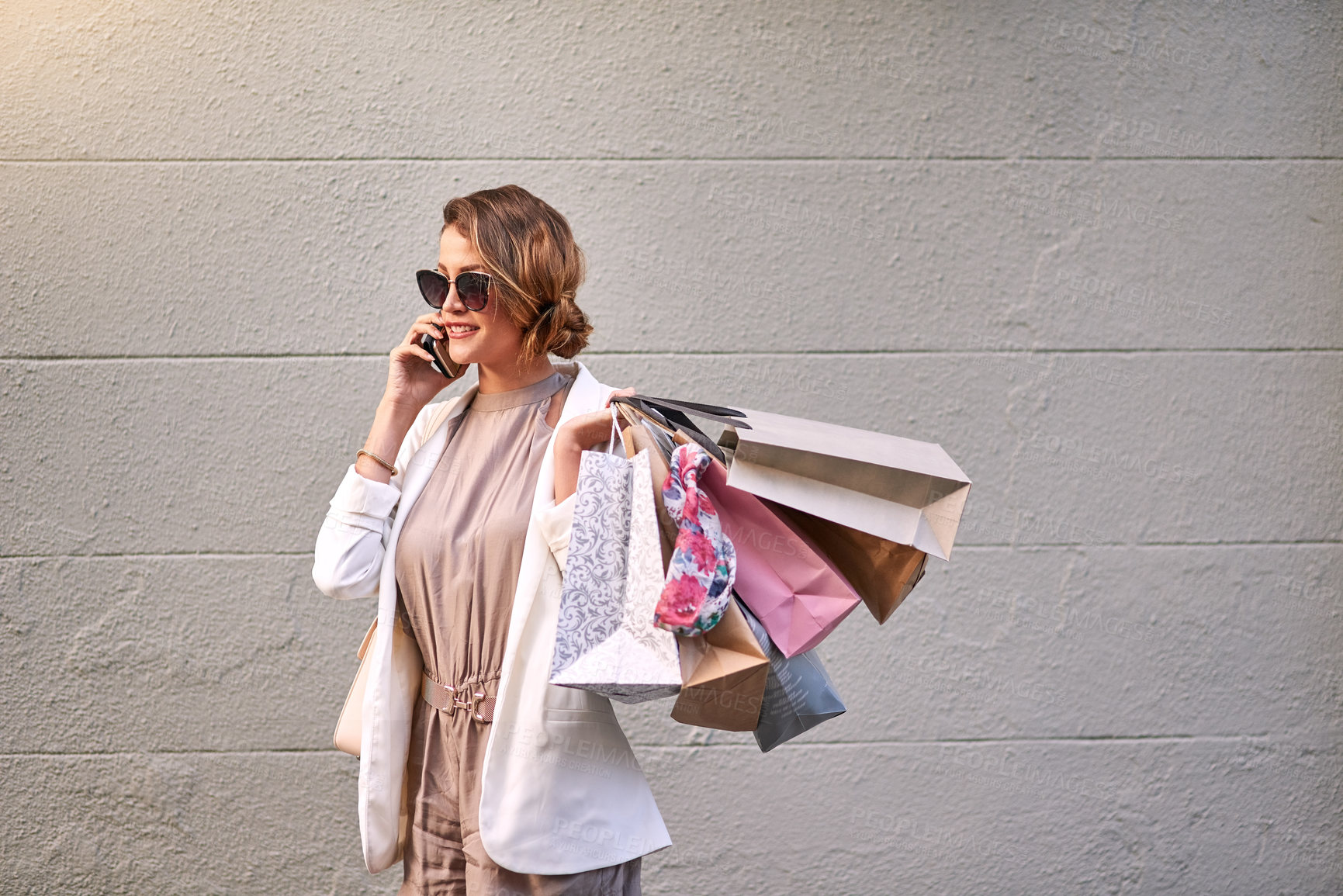 Buy stock photo Trendy woman talking on a phone call after a shopping spree in the city. Young female looking stylish, enjoying her free time with retail therapy downtown, smiling and happy about a sale and purchase