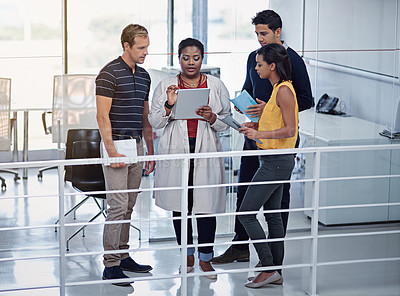 Buy stock photo Shot of a group of colleagues working together on a digital tablet in an office