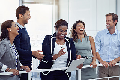 Buy stock photo Shot of a group of laughing colleagues working together on a digital tablet in an office