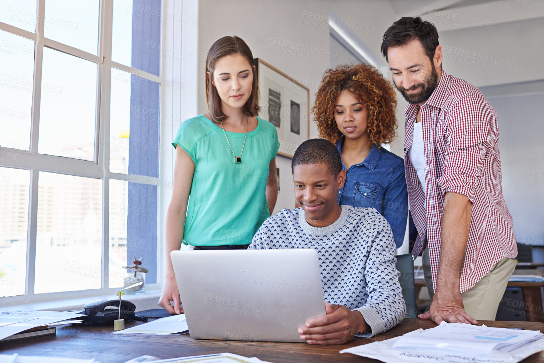 Buy stock photo Cropped shot of three young designers gathered around a laptop in the boardroom