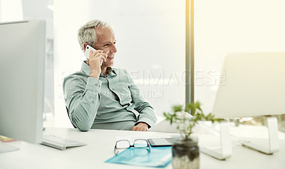 Buy stock photo Shot of a mature businessman talking on the phone while working at his desk in an office