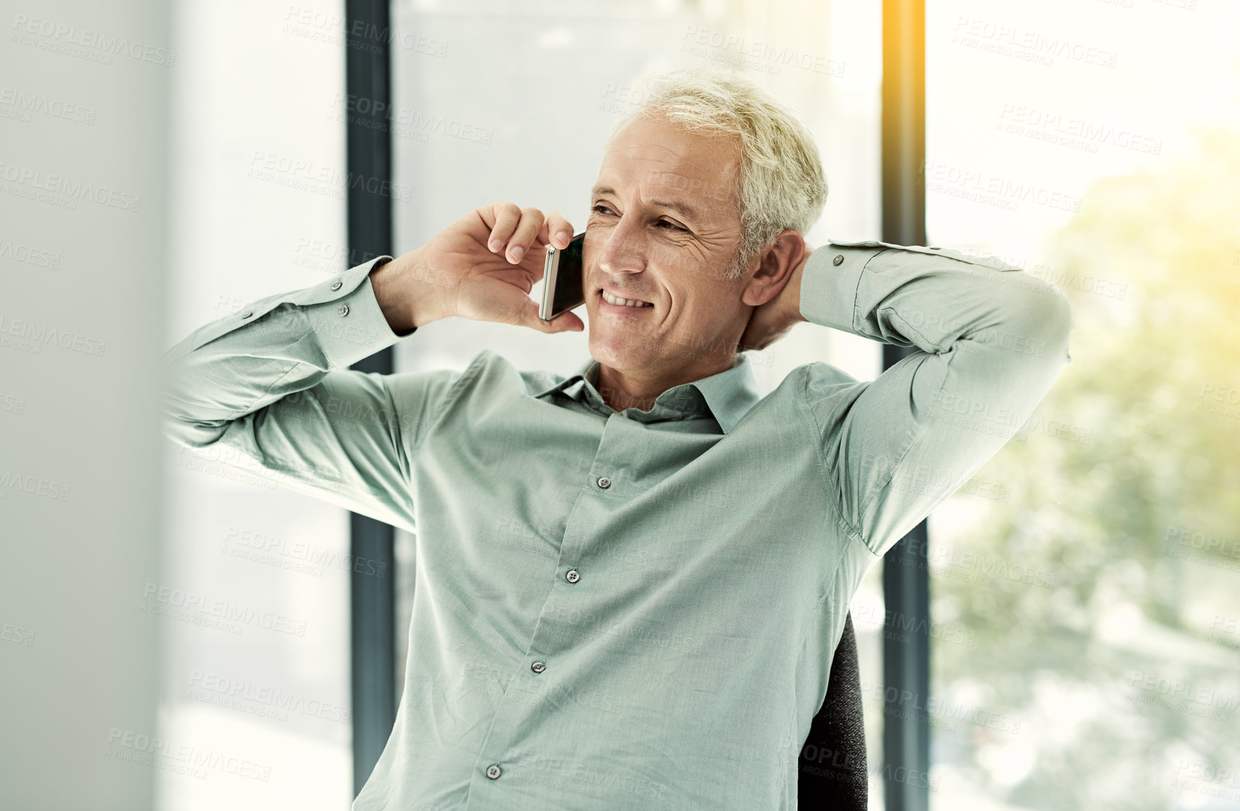 Buy stock photo Shot of a mature businessman talking on the phone while working at his desk in an office