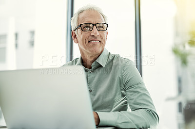 Buy stock photo Shot of a mature businessman working on a computer at his desk in an office