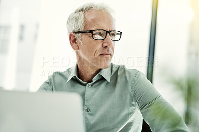 Buy stock photo Shot of a mature businessman working on a computer at his desk in an office