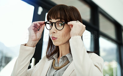 Buy stock photo Shot of a young businesswoman adjusting her glasses while working in an office