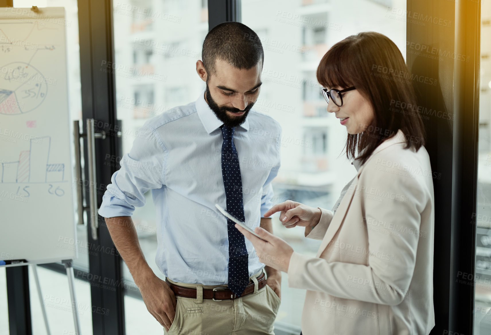 Buy stock photo Shot of two colleagues using a digital tablet while standing together in an office