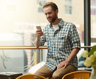 Buy stock photo Shot of a young man using a cellphone in a cafe