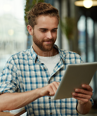 Buy stock photo Shot of a young man using a digital tablet in a cafe