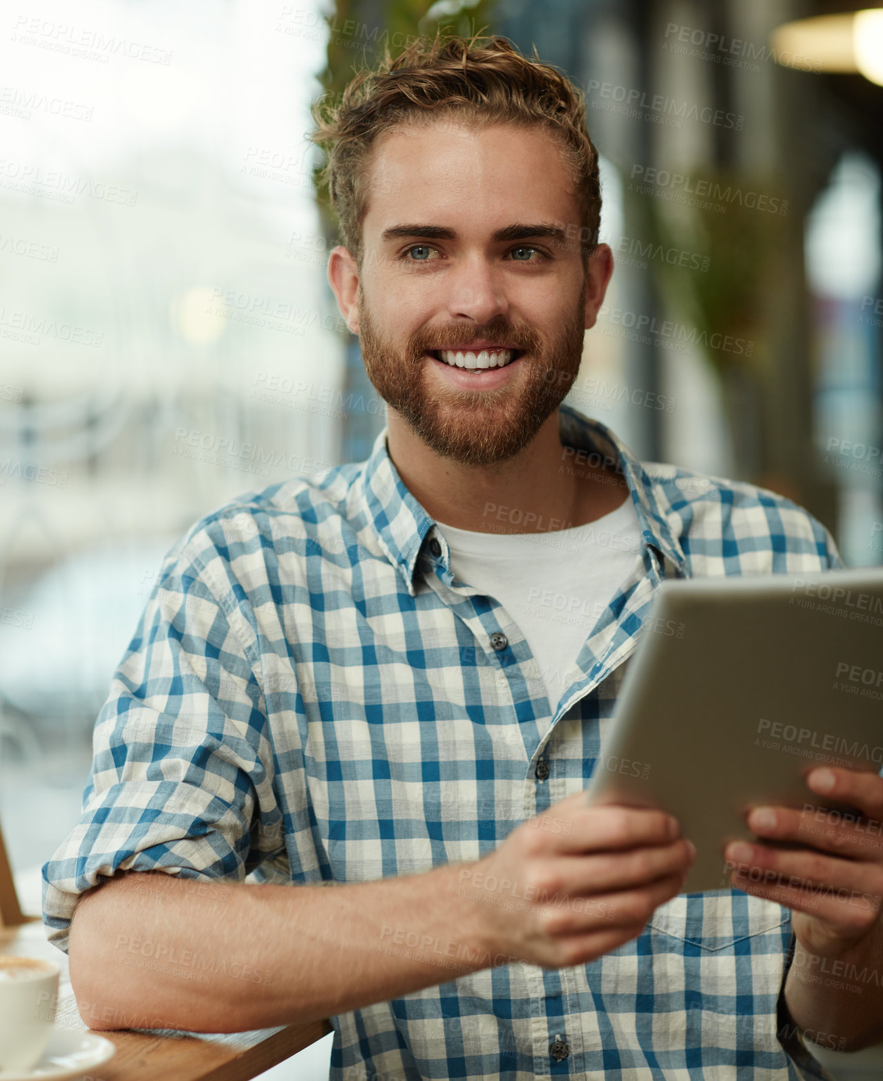 Buy stock photo Shot of a young man using a digital tablet in a cafe