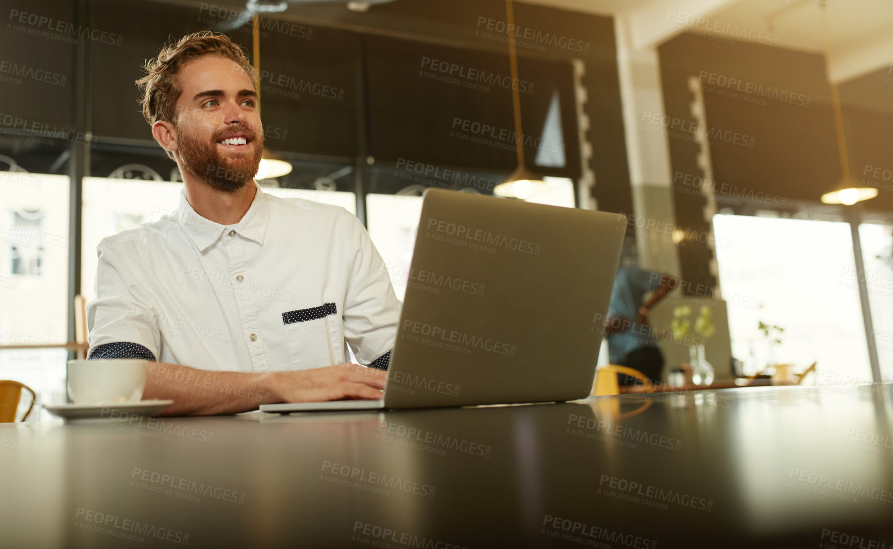 Buy stock photo Shot of a young man using a laptop in a cafe