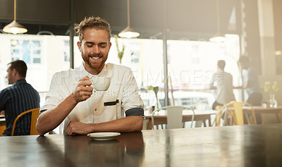 Buy stock photo Shot of a young man sitting at a table in a cafe