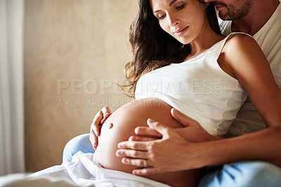 Buy stock photo Shot of a husband and pregnant wife sitting together in a bedroom