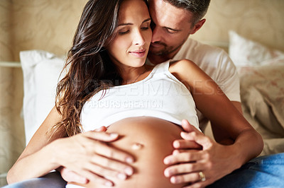 Buy stock photo Shot of a husband and pregnant wife sitting together in a bedroom