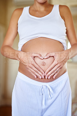 Buy stock photo Shot of a pregnant woman holding her belly with her hands forming a heart shape
