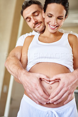 Buy stock photo Shot of a husband and wife holding her pregnant belly together