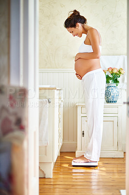 Buy stock photo Shot of a pregnant woman standing on a scale