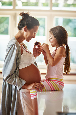 Buy stock photo Shot of a pregnant woman and young girl eating cupcakes together