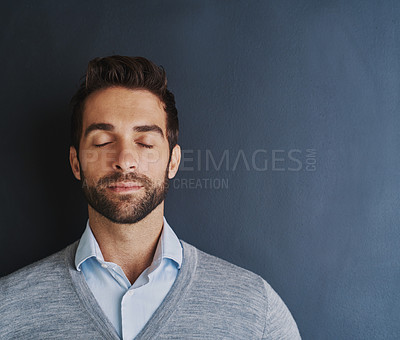 Buy stock photo Shot of a handsome young businessman posing against a dark background