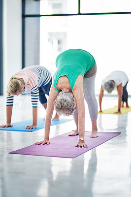 Buy stock photo Shot of a group of women doing yoga indoors