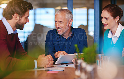 Buy stock photo Shot of businesspeople using a digital tablet in a meeting