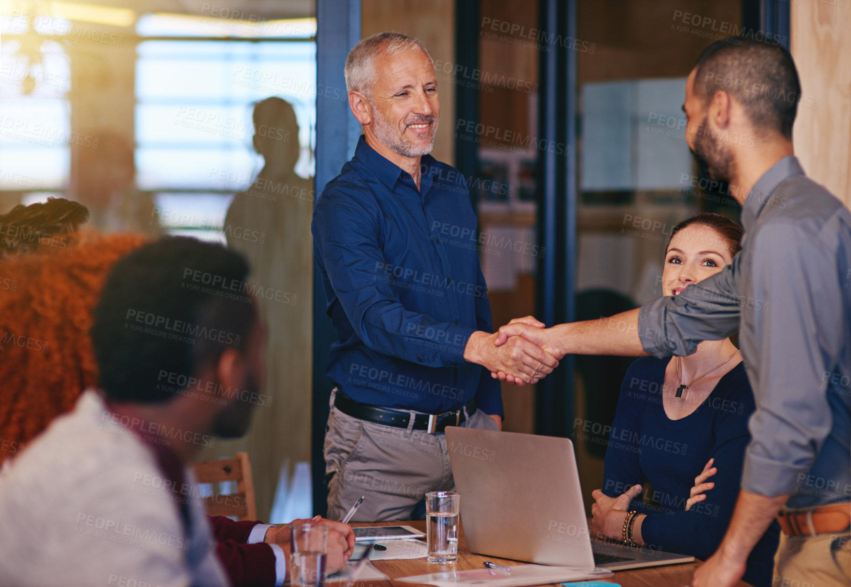 Buy stock photo Shot of colleagues shaking hands in an office meeting