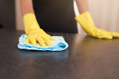 Buy stock photo Cropped shot of a person wearing rubber gloves while wiping a kitchen table with a cloth at home