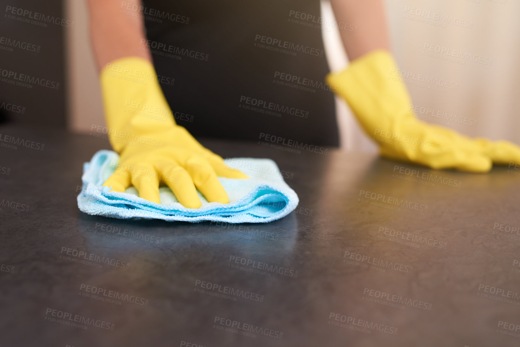 Buy stock photo Cropped shot of a person wearing rubber gloves while wiping a kitchen table with a cloth at home