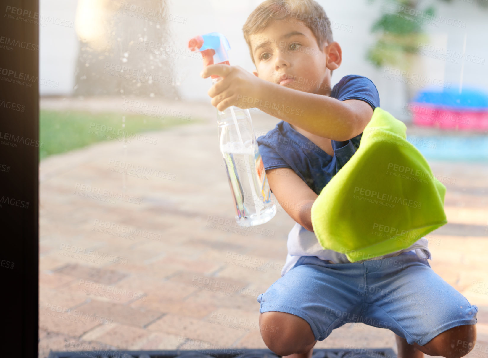 Buy stock photo Shot of a little boy washing a glass door at home