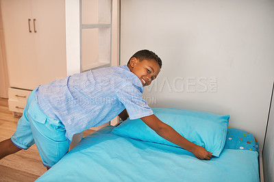 Buy stock photo Portrait of a young boy making up a bed