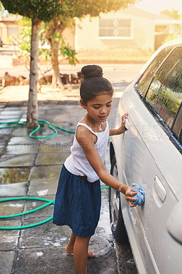 Buy stock photo Shot of a young girl busy cleaning a car outside