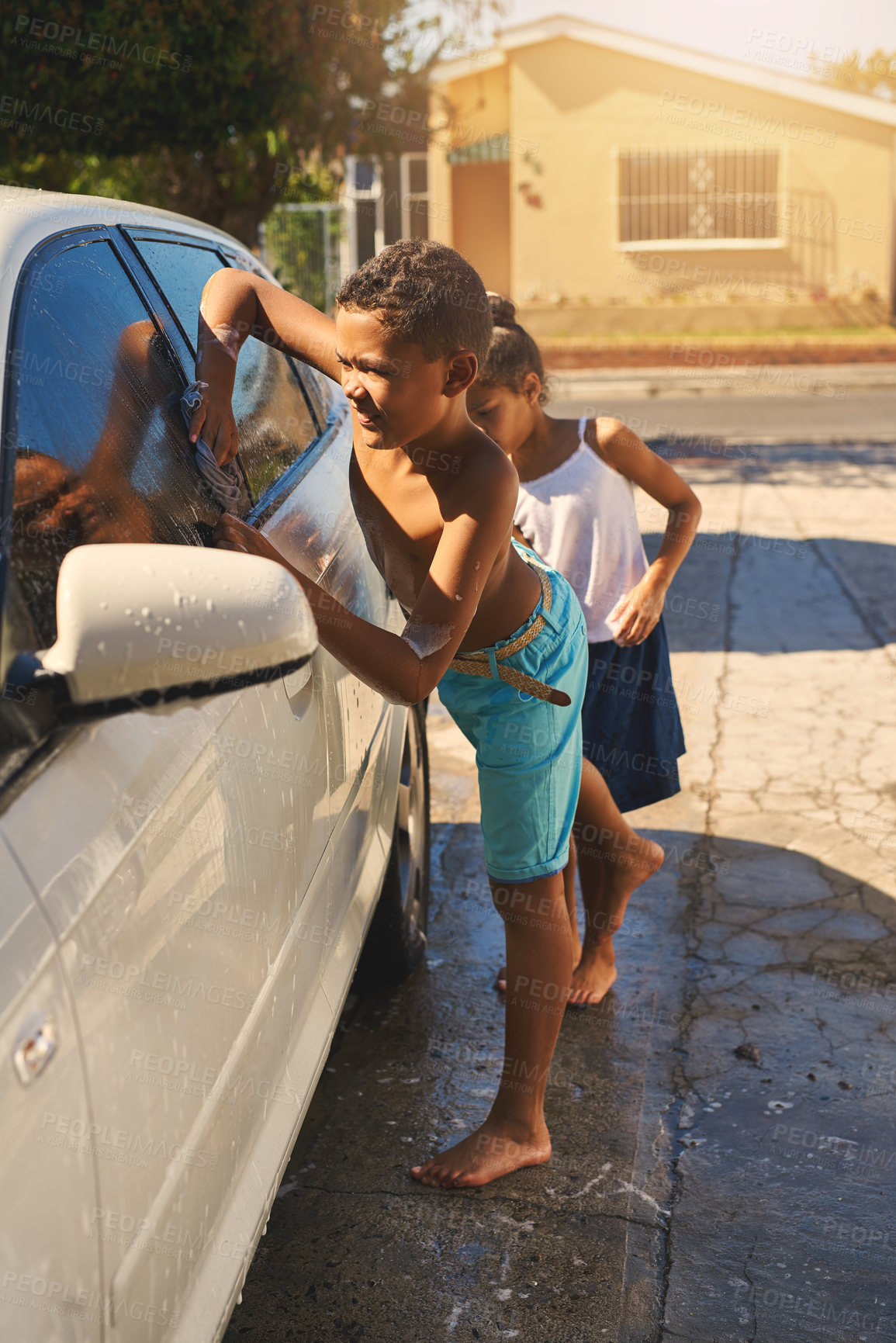 Buy stock photo Boy, carwash and vehicle in home, soap and driveway for chores. Siblings, duty and cleaning car for pocket money and responsibility, foam wash and child on weekend for help with task for family