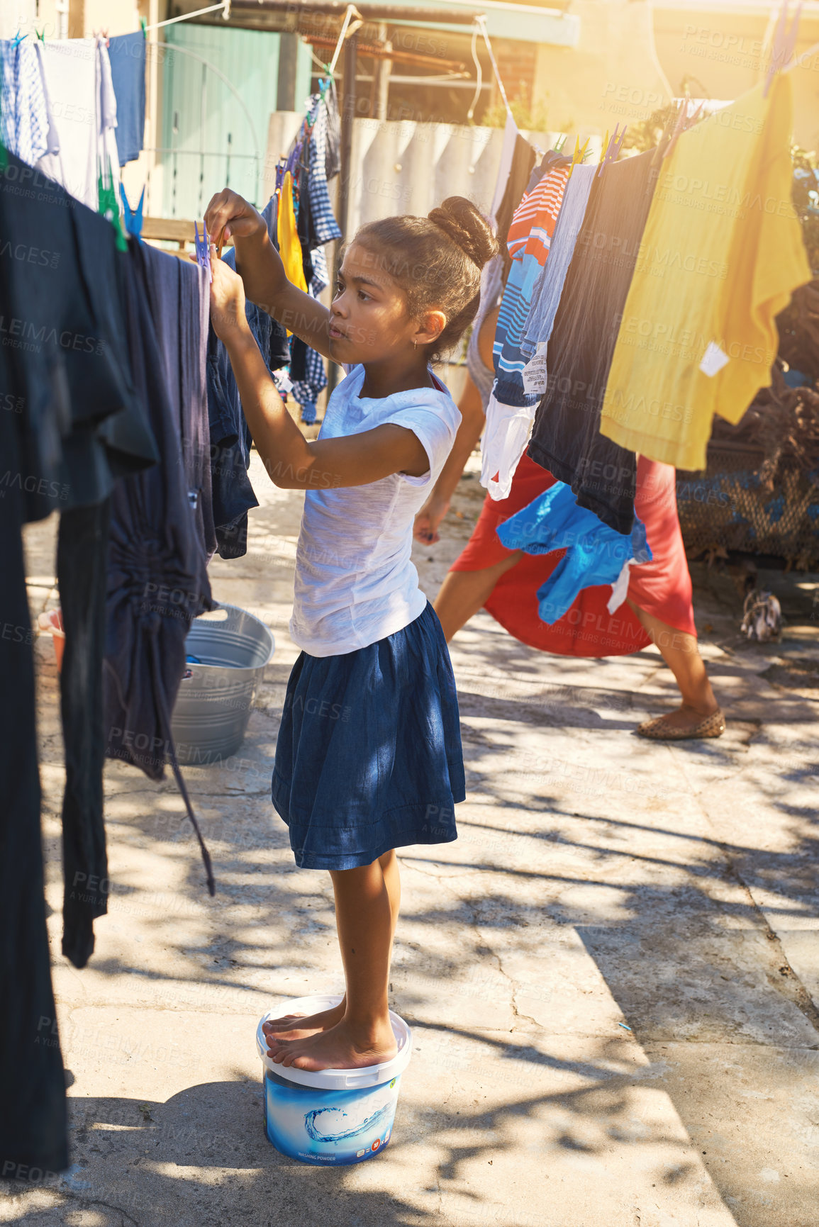 Buy stock photo Child, hanging and laundry washing with outdoor sun for housekeeping chores, discipline or task. Girl, clothing and backyard line for home or learning responsibility in garden, helping or hygiene