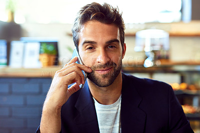 Buy stock photo Portrait of a handsome young man talking on a phone in a cafe