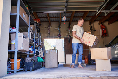 Buy stock photo Shot of a man carrying a box in a garage