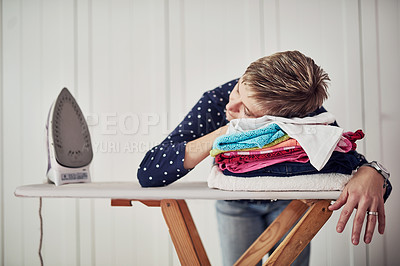 Buy stock photo Shot of a woman with her head down on a pile of clothes on an ironing board