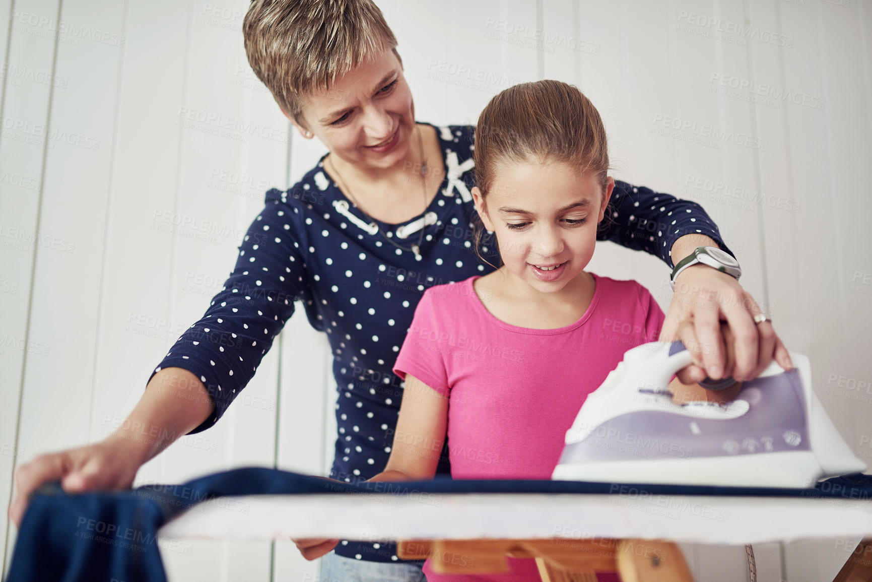 Buy stock photo Shot of a mother helping her daughter with some ironing