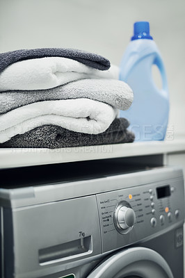 Buy stock photo Washing machine with stacked, folded towels and detergent on a countertop inside a scullery room at home. Clean clothes after washing, cleaning, drying. Using household equipment for hygiene.