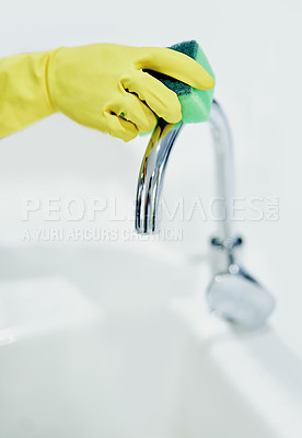 Buy stock photo Closeup of a persons hand in a yellow glove cleaning the kitchen tap and sink with a sponge and disinfecting surfaces. Zoom in on hand of a cleaner practicing good hygiene and scrubbing a shiny tap 