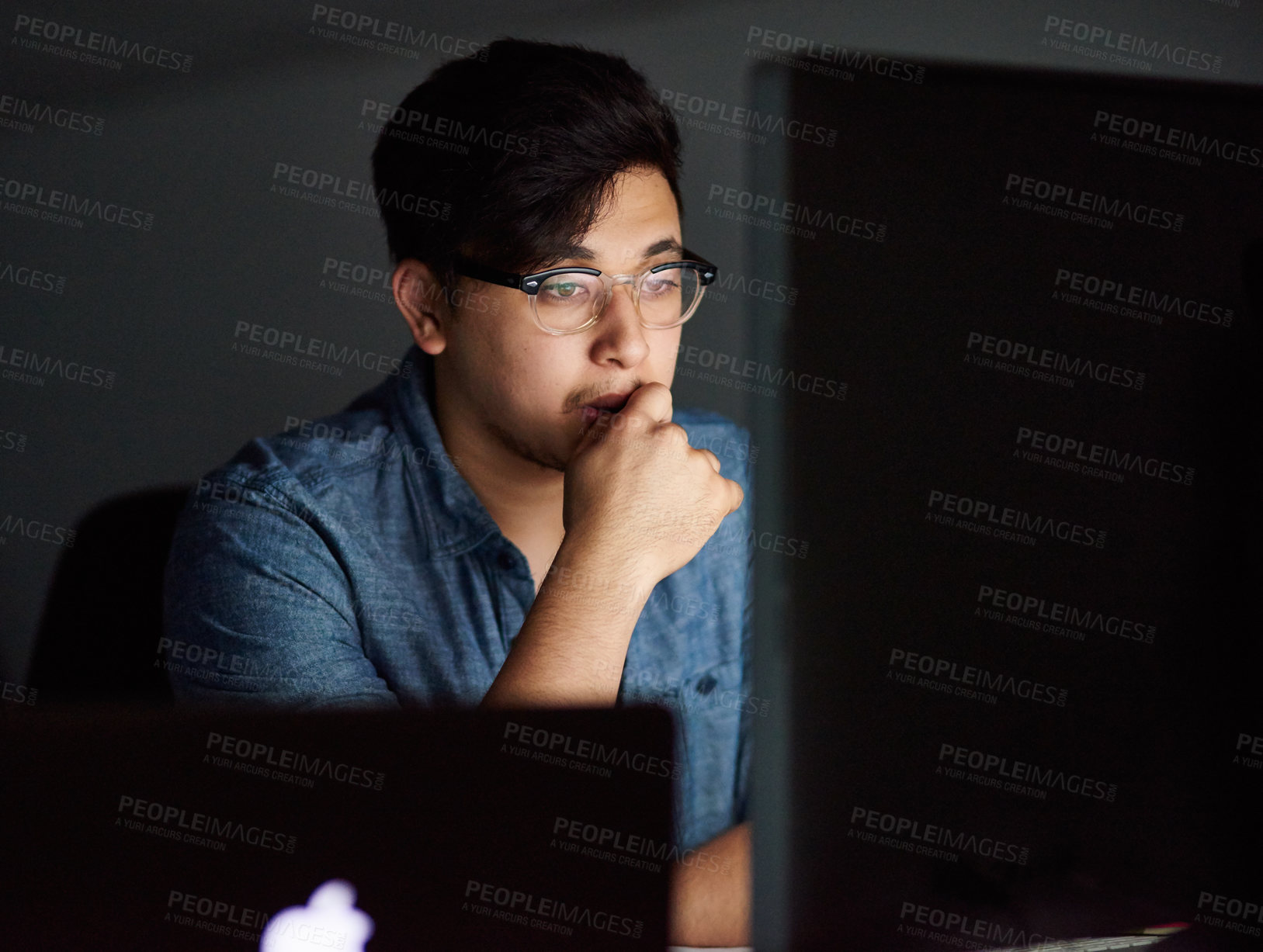 Buy stock photo Cropped shot of a young man working late in his office