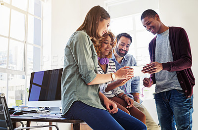 Buy stock photo Shot of colleagues using a digital tablet with headphones plugged into it at work
