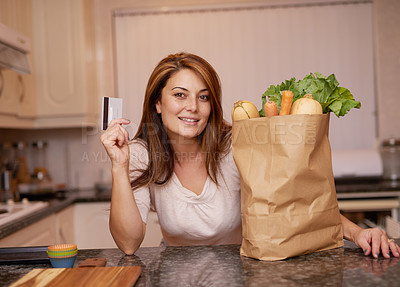 Buy stock photo Portrait of a young woman standing with a credit card and groceries