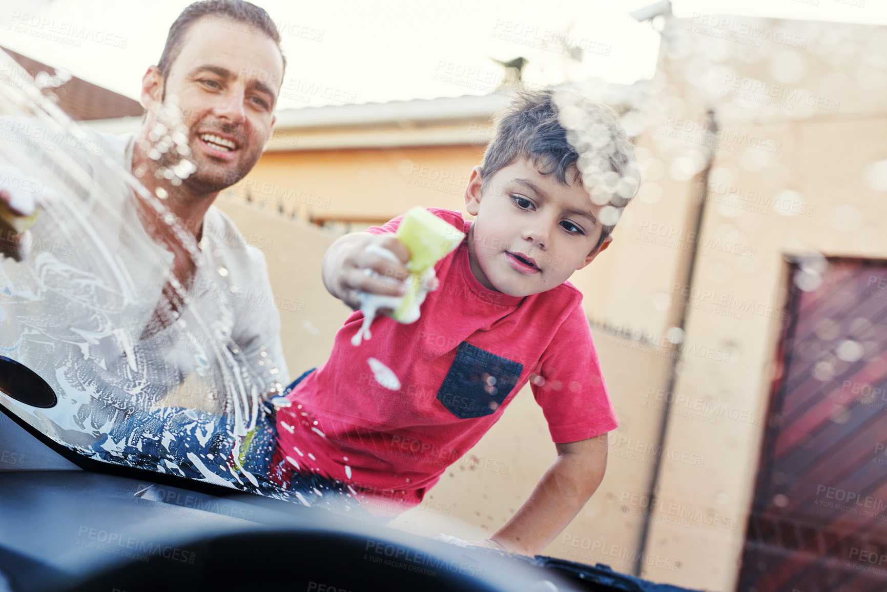 Buy stock photo Shot of a family washing their car in the driveway